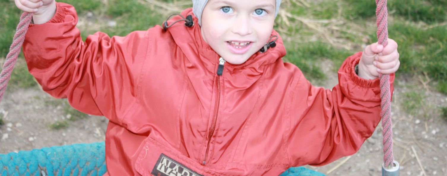 Person mit roter Jacke auf einer Schaukel