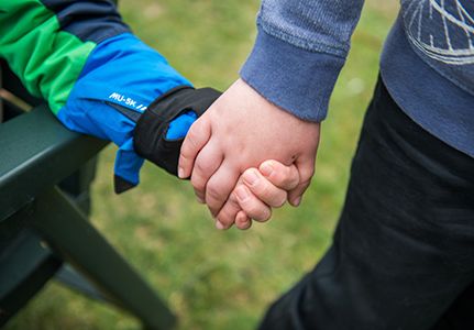 Zwei Personen halten sich an den Händen.